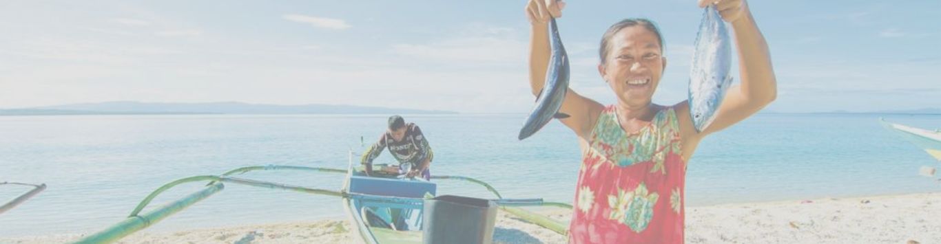 SALT's brand image of a woman holding two fish with a boat, man, and ocean in the background.