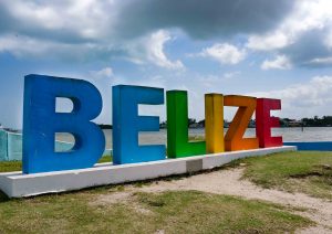 Belize sign with water and cloudy sky in the background