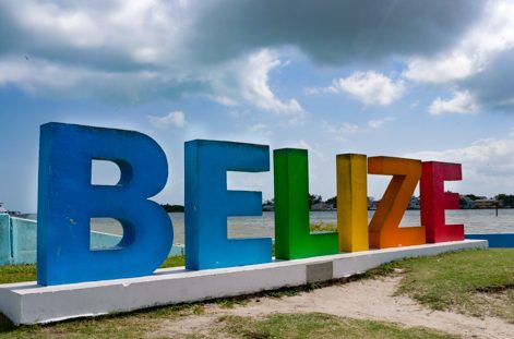 Belize sign with water and cloudy sky in the background